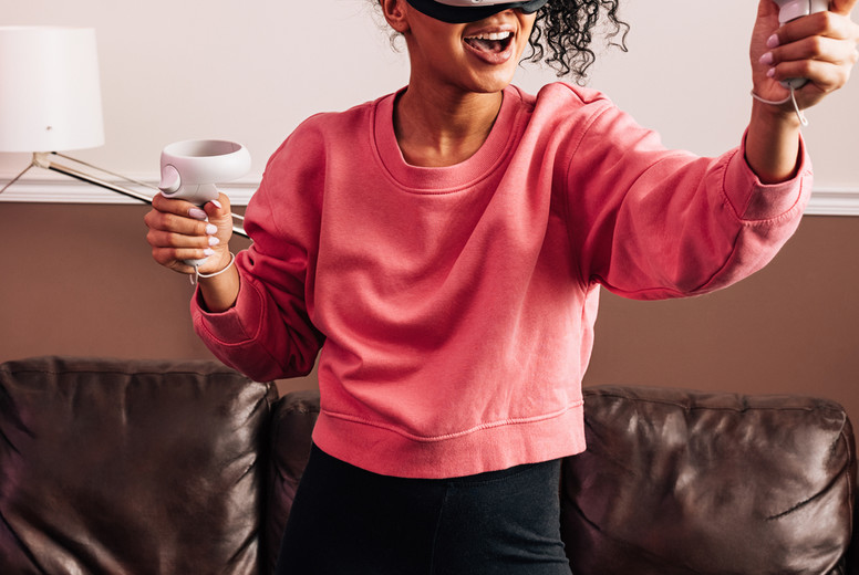 Woman with VR goggles and controllers in living room