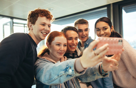 Smiling students clicking selfies in high school