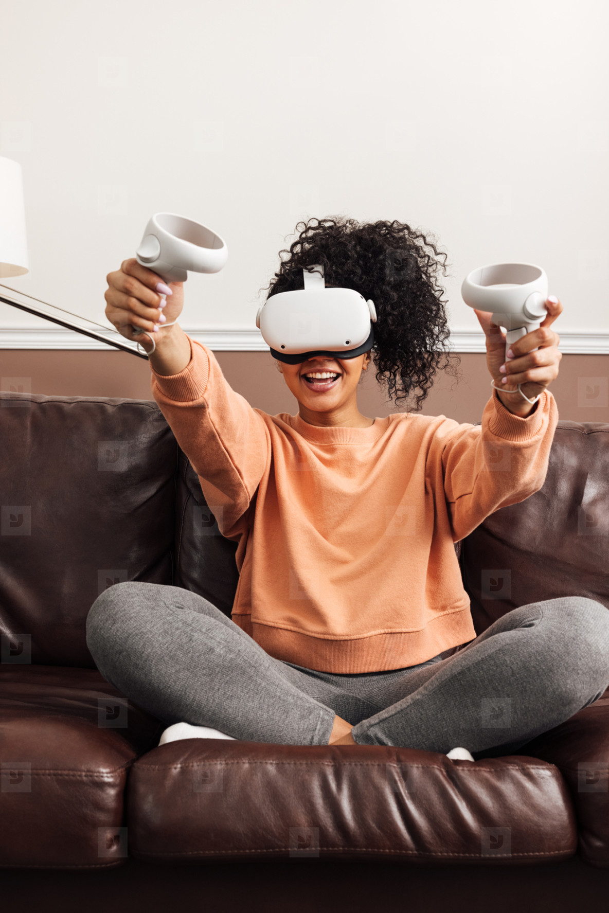 Young happy woman sitting on couch using VR set