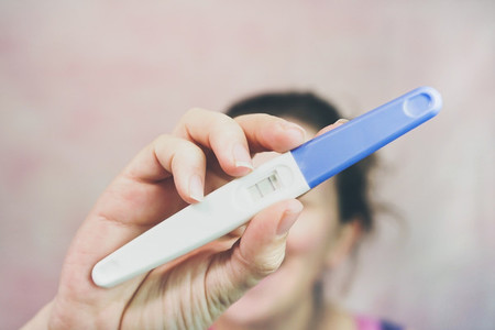 Young happy woman holding a positive pregnancy test