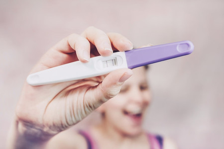 Young happy woman holding a positive pregnancy test