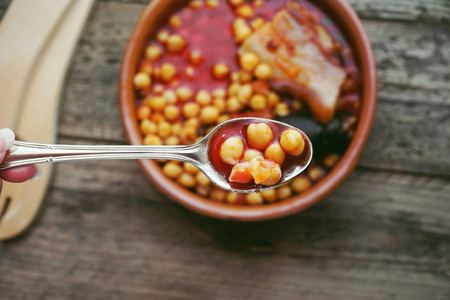Flat of chickpeas  sausage and bacon in a crockpot by wooden spo
