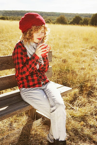 A young woman in red plaid shirt with a wool cap and scarf takin