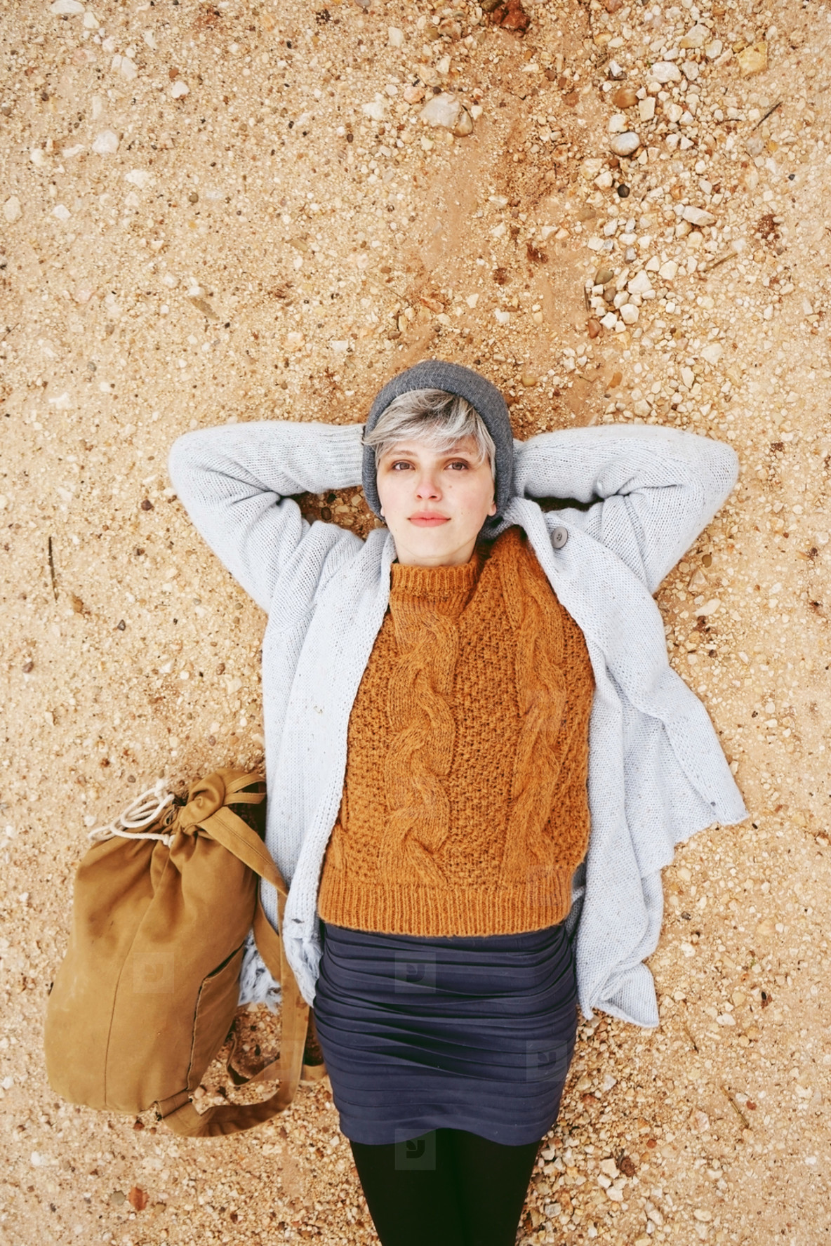 An adventurer young caucasian woman lying on grit ground beside