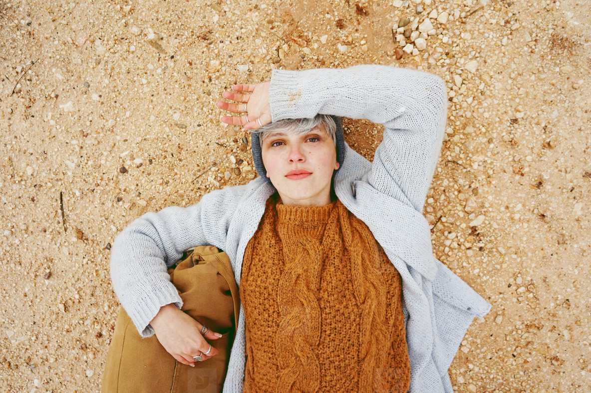 An adventurer young caucasian woman lying on grit ground beside