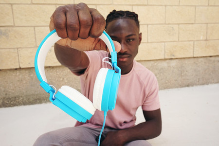 Young man leaning on brick wall wearing headphones