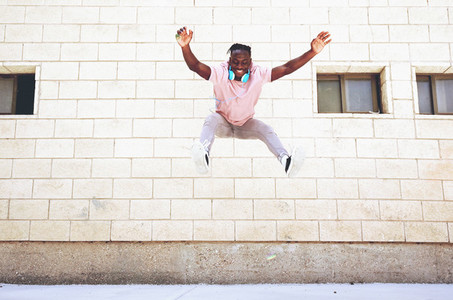Young man jumping in the street wearing headphones
