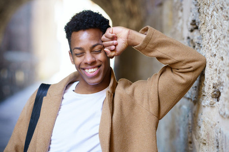 Happy young black man laughing in urban background