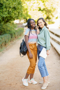 Two multiethnic women posing together with colorful casual clothing