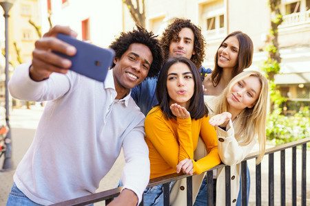 Multi ethnic group of friends taking a selfie outdoors with a smartphone