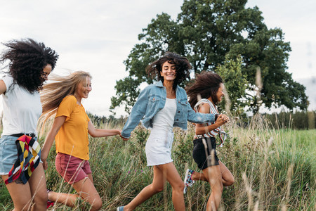 Group of a happy woman running and jumping outdoors  Female friends having fun on a field