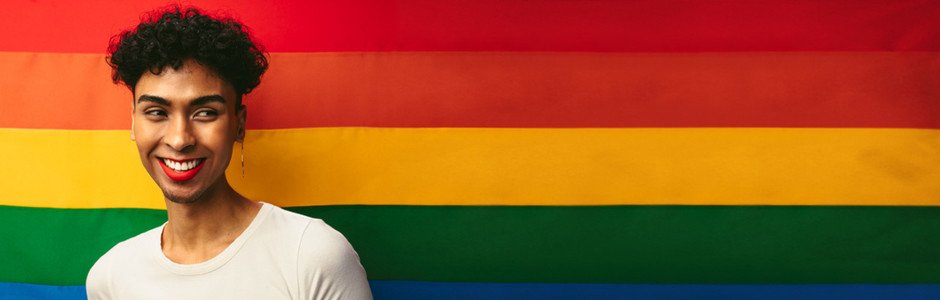 Gay man smiling against pride flag