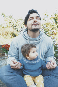 Young dad enjoying a sunny day with his baby in the garden
