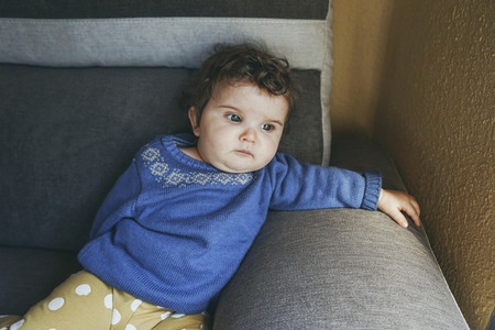 sad and tired baby sitting in a sofa