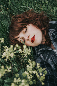 Young beautiful woman resting in a field of flowers