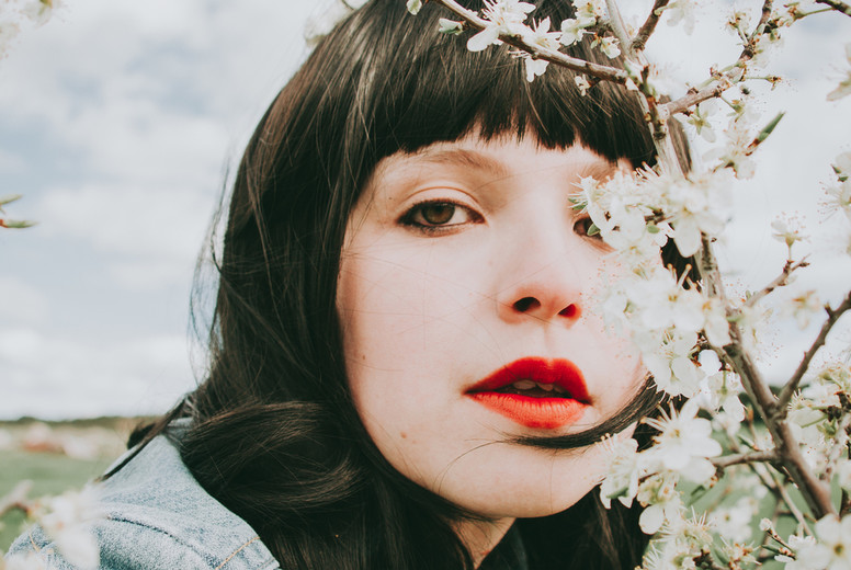 Beautiful young woman posing near spring flowers