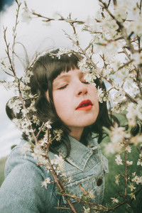 Beautiful young woman posing near spring flowers