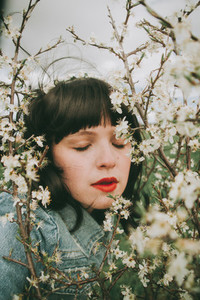 Beautiful young woman posing near spring flowers