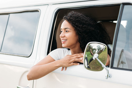 Smiling mixed race woman looks out from van window enjoying a road trip
