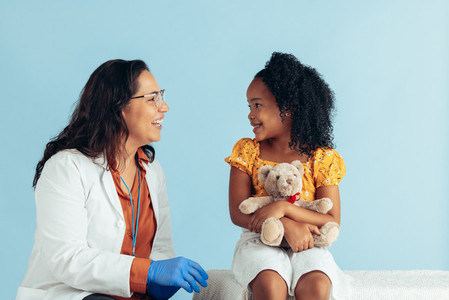 Smiling pediatrician talking with cute patient