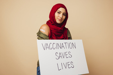 Muslim woman with Vaccination saves lives banner