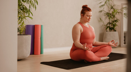 Woman in sportswear meditating in home gym