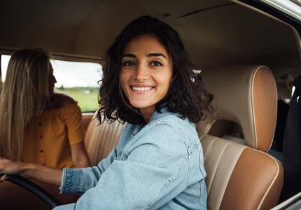 Smiling brunette woman on driver seat looking at camera