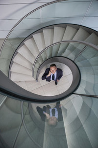 Portrait businessman talking on smart phone below spiral staircase