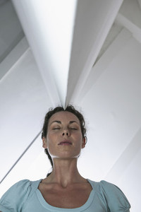Serene businesswoman standing below angled ceiling