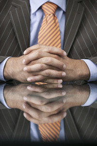 Close up businessman with hands clasped on reflective table
