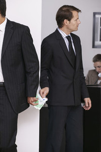 Businessmen exchanging money secretly in office