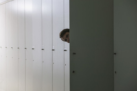 Portrait playful businessman peering from inside locker