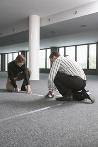 Businessmen measuring and marking floor in new office