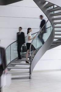 Young businesswoman ascending spiral staircase in office