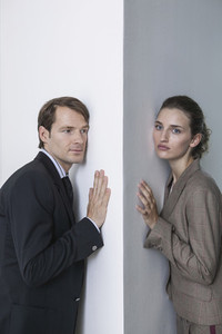 Portrait businessman and businesswoman at office wall corner