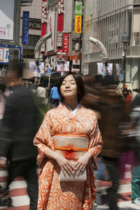 Serene young woman in kimono in sunny bustling city street Kyoto Japan