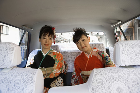 Portrait Japanese women in kimonos riding in back seat of car
