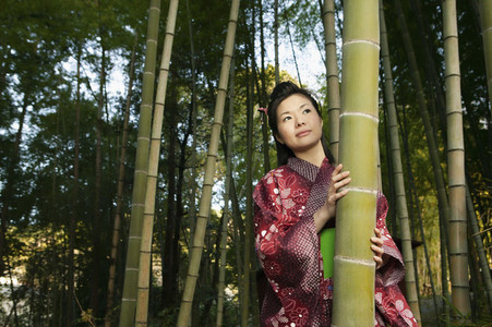 Portrait beautiful curious young woman in Japanese kimono among bamboo trees