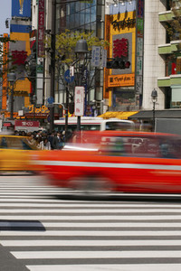 Cars speeding over crosswalk in sunny city Tokyo Japan