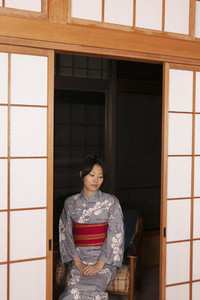 Beautiful serene young woman in kimono at shoji screen doors