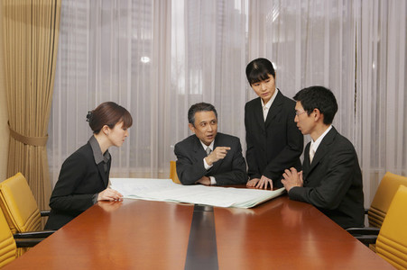 Business people discussing blueprints in office conference room