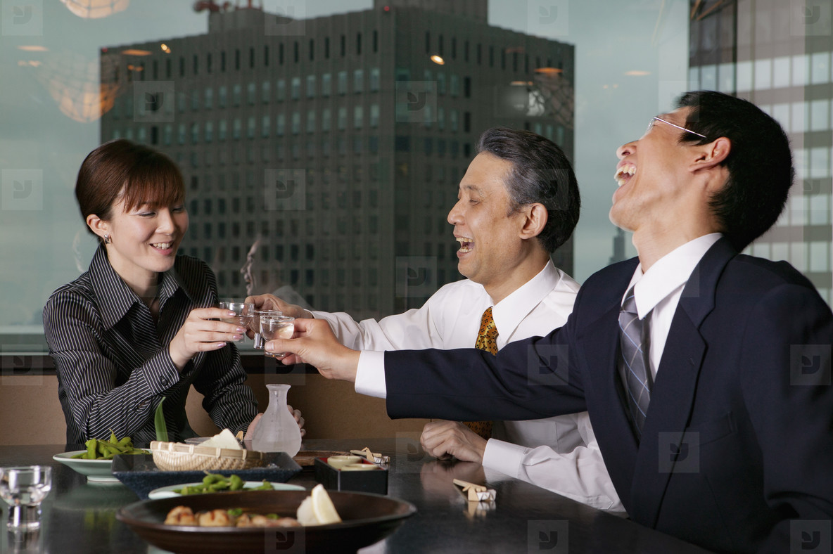 Happy business people toasting sake in highrise restaurant
