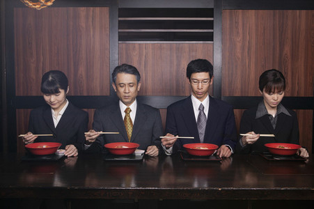 Japanese business people eating with chopsticks in restaurant
