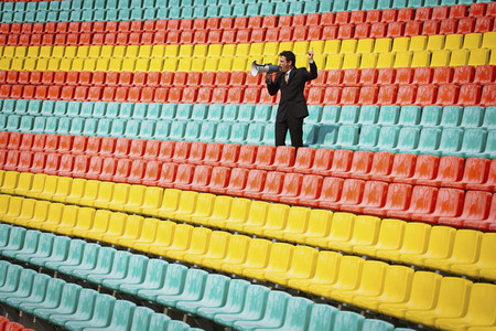 Man with megaphone in colorful soccer stadium seats