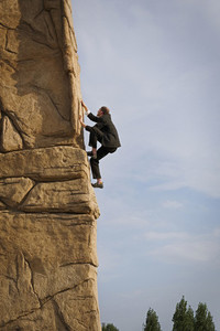 Businessman climbing steep rock face