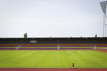 Man running on track at sunny soccer stadium