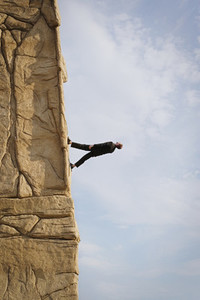 Businessman walking up steep rock face