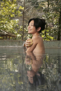 Beautiful happy young woman soaking in Onsen pool