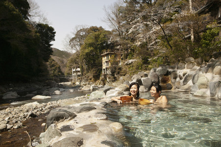 Happy young women soaking in sunny Onsen pool Izu Japan