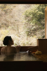 Serene young woman in Onsen pool looking out window